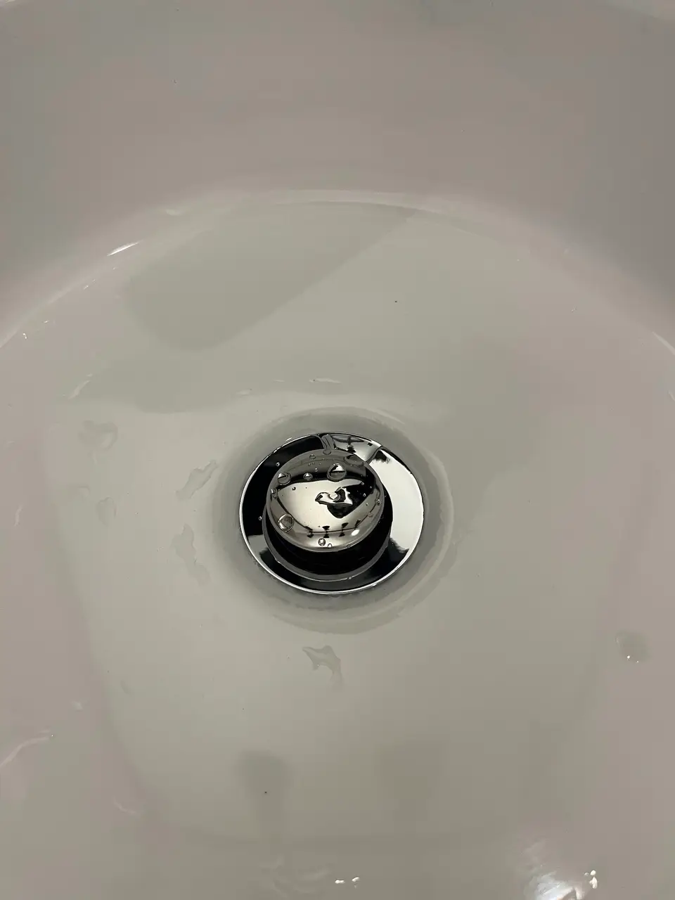 Bonde chromée posée au fond d'un lavabo à Nice